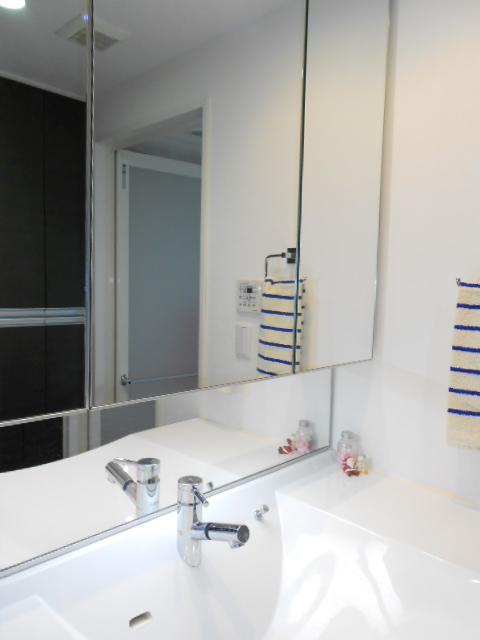 Wash basin, toilet. Shooting vanity triple mirror with storage. Bright is a wash room is equipped with a light even under the three-sided mirror.