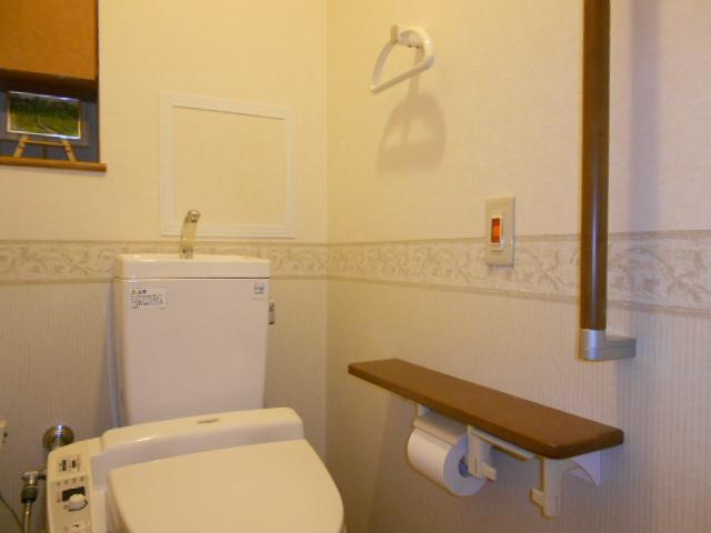 Toilet. It is a handrail with a toilet. The wall is also housed.