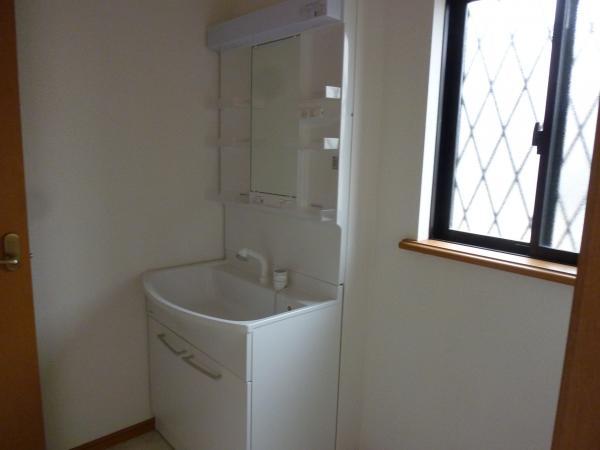 Wash basin, toilet. Bright wash room with a window.