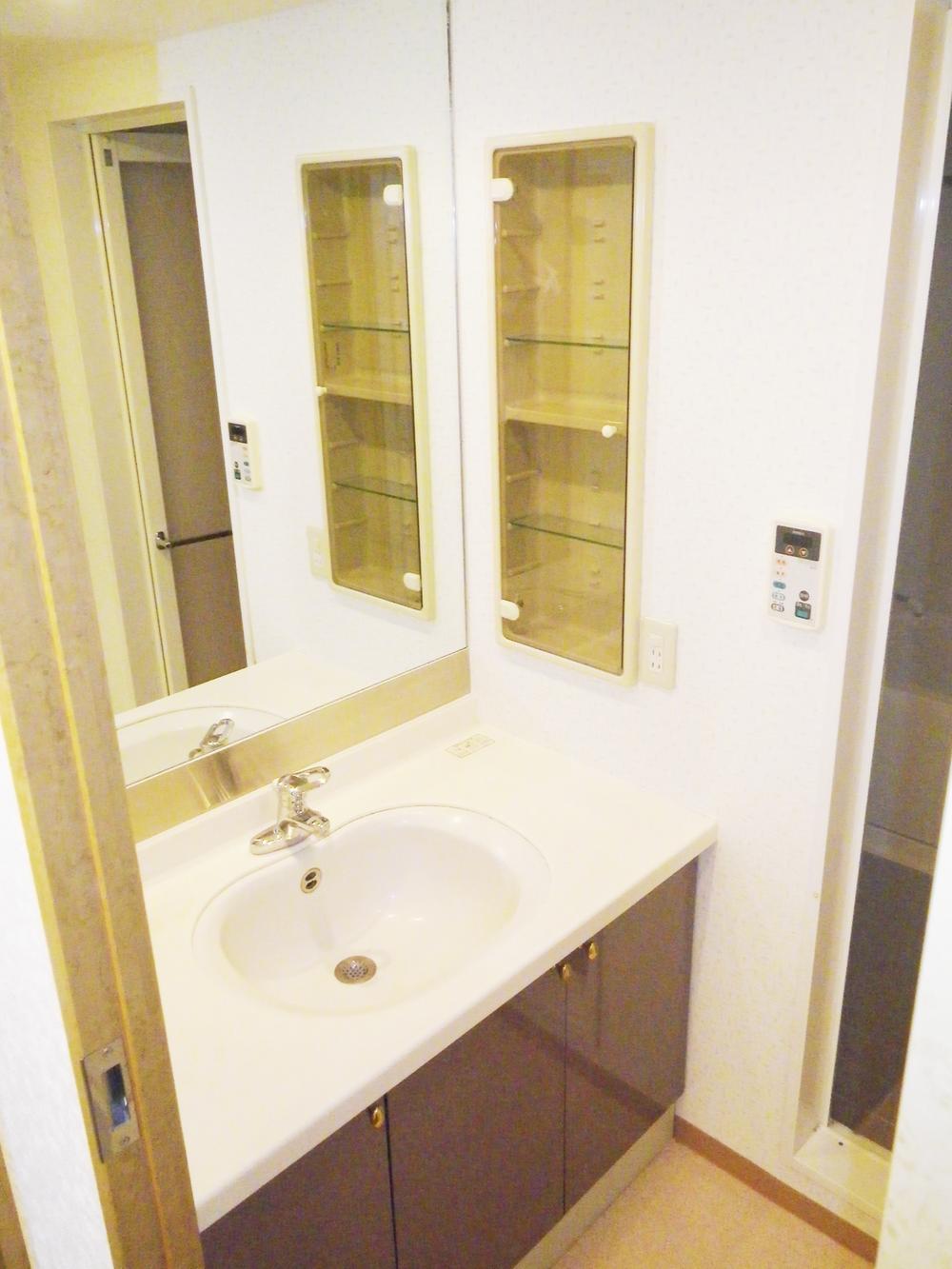 Wash basin, toilet. It is a large mirror storage rich washroom