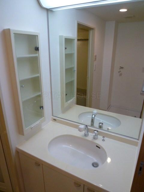 Wash basin, toilet.  [Washroom] Vanity with a wide mirror