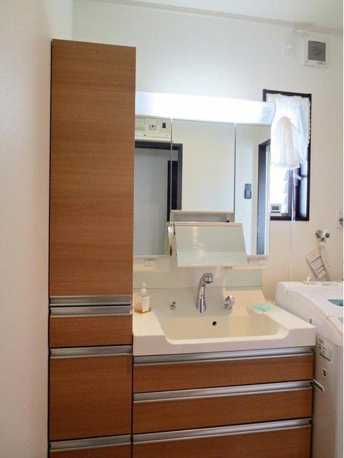 Wash basin, toilet. Wash basin also sticking to three-sided mirror + is a handy with storage shelf