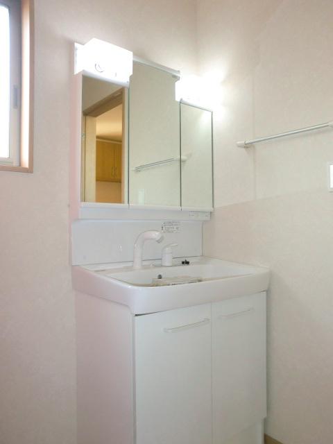 Wash basin, toilet. Behind it is housed in a three-sided mirror type