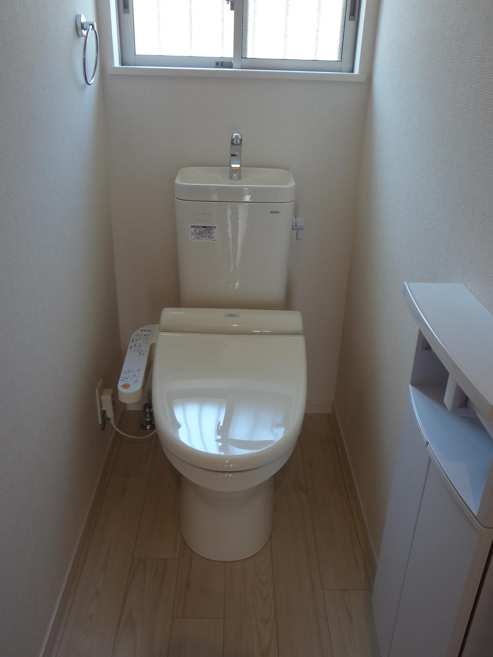 Toilet. There is a storage box with paper holder