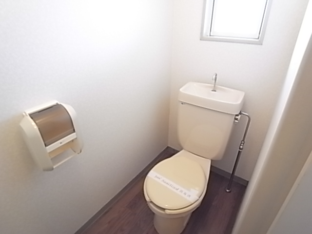 Toilet. It is bright with windows. 