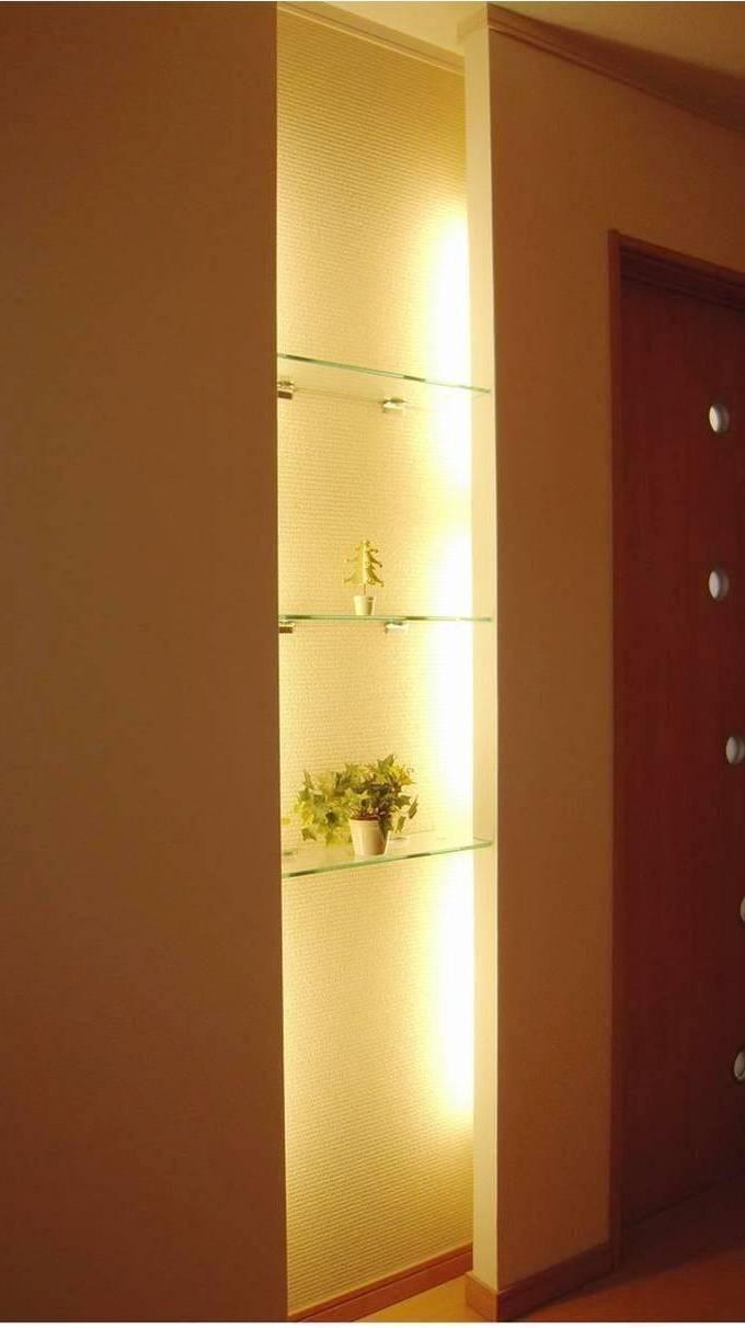 Entrance. Glass shelves with lighting in front of the entrance. Side-by-side favorite miscellaneous goods in a stylish space