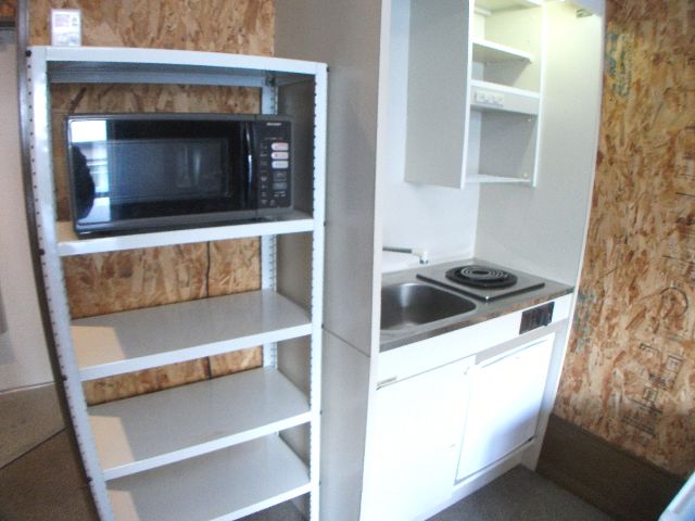 Kitchen. There is also a shelf and microwave ovens.