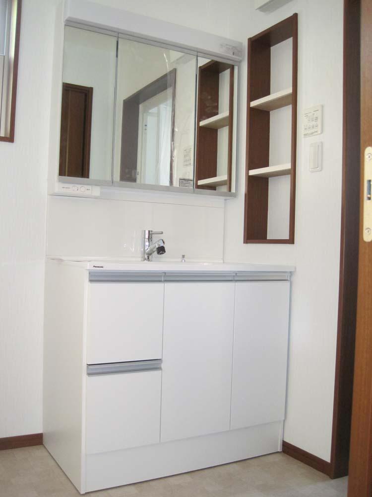 Wash basin, toilet. Vanity with a triple mirror back storage