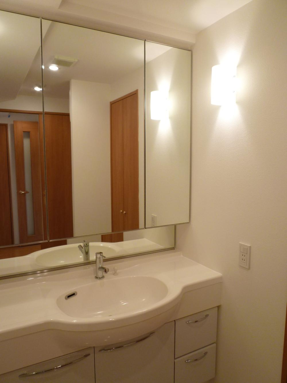 Wash basin, toilet. There is three-sided mirror back storage
