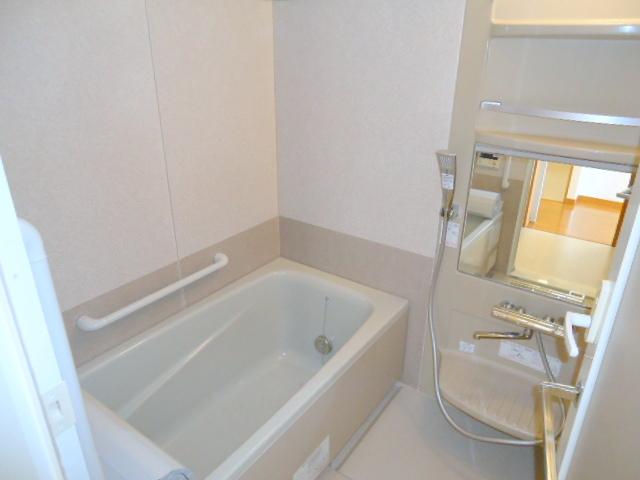 Bathroom. It features a large mirror and a bathtub handrail.