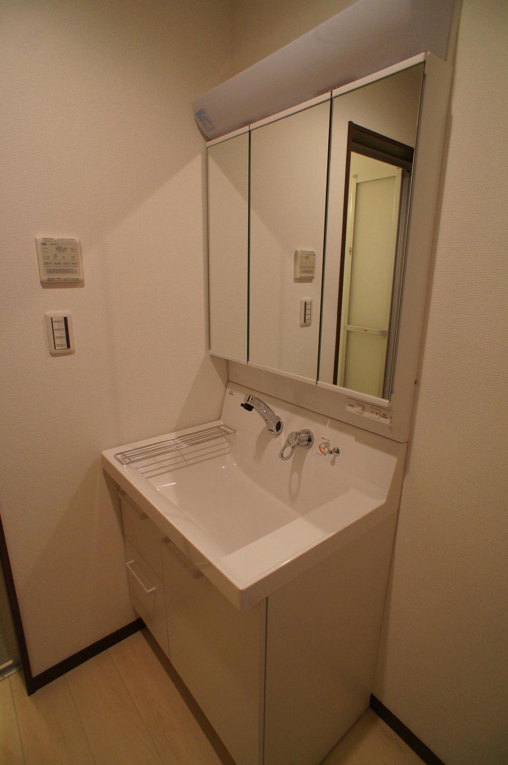 Wash basin, toilet. Basin is a vanity with a three-sided mirror and shower