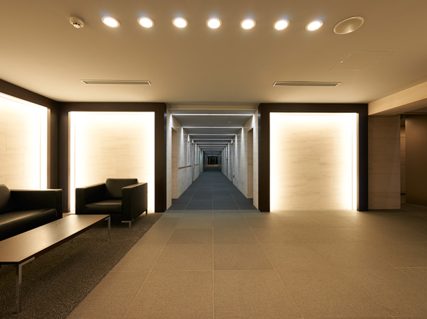 Buildings and facilities. When you set foot in the entrance hall of the two-tier atrium, Complete change from the cool atmosphere of the appearance. Indirect lighting that has been charged to the trim of ebony, Illuminate soften the wall of limestone, It spreads friendly space, such as a hotel. (Lounge Rendering)