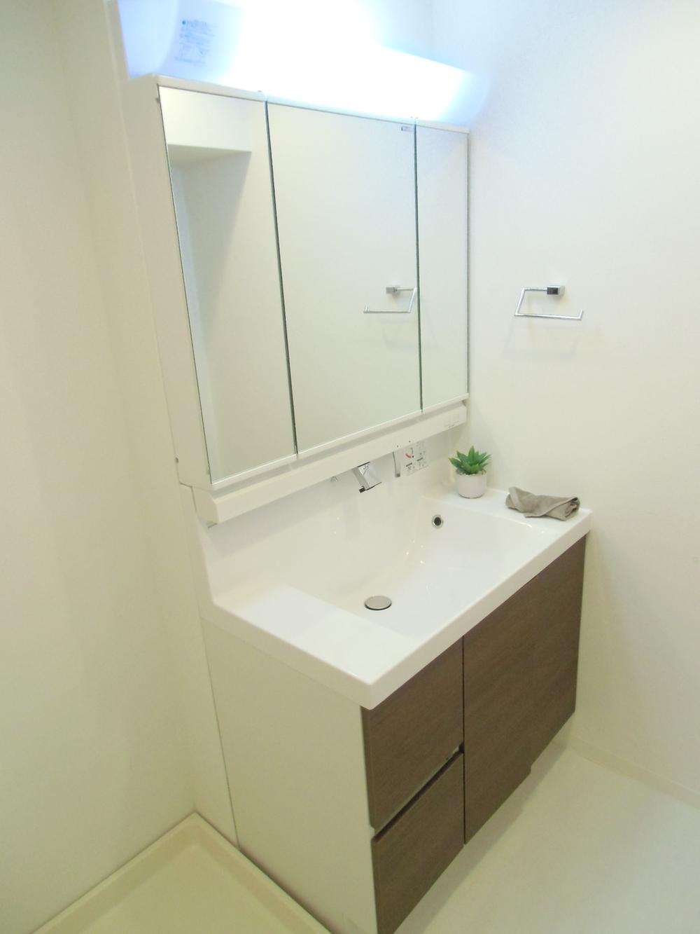 Wash basin, toilet. Three-sided mirror with wide basin cabinet