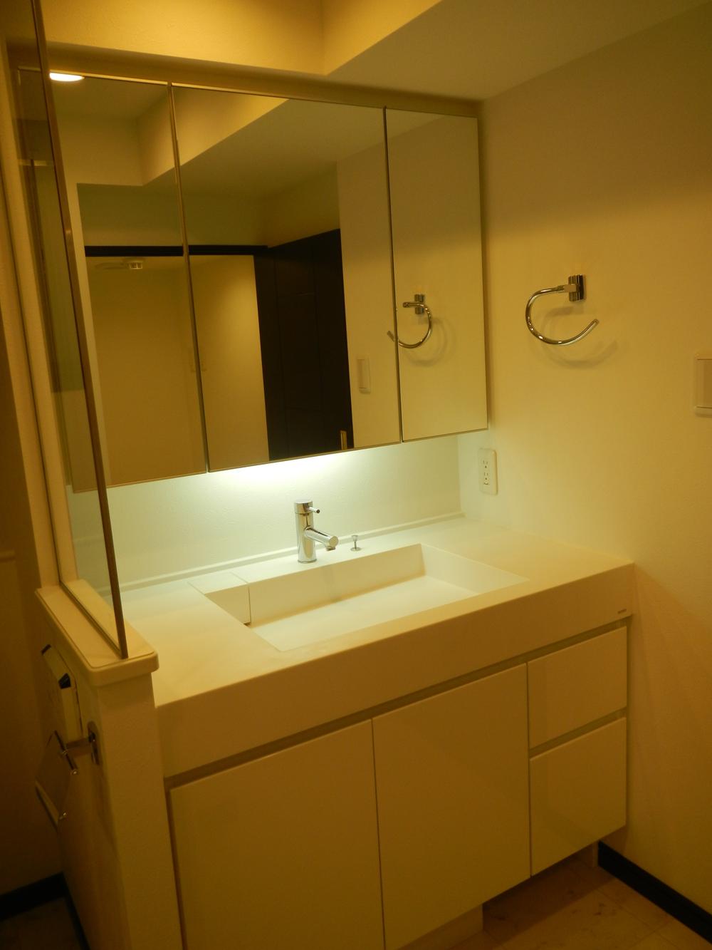 Wash basin, toilet. Three-sided mirror with storage vanity