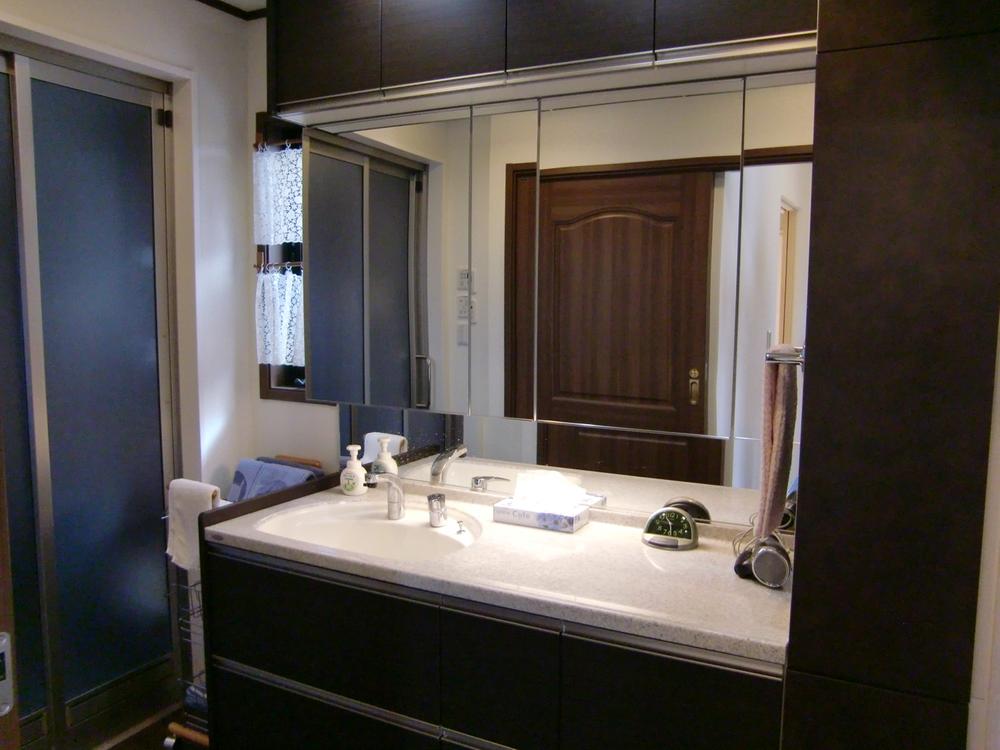 Wash basin, toilet. There is a large mirror, Storage is also rich wash room