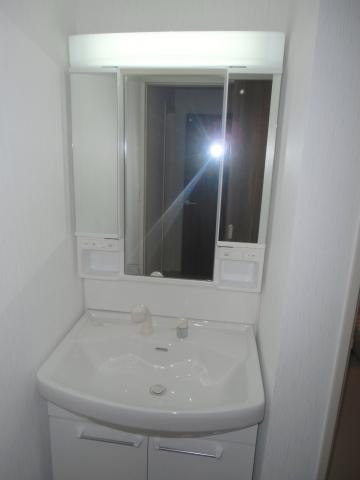 Wash basin, toilet. Of the three-sided mirror is a wash basin