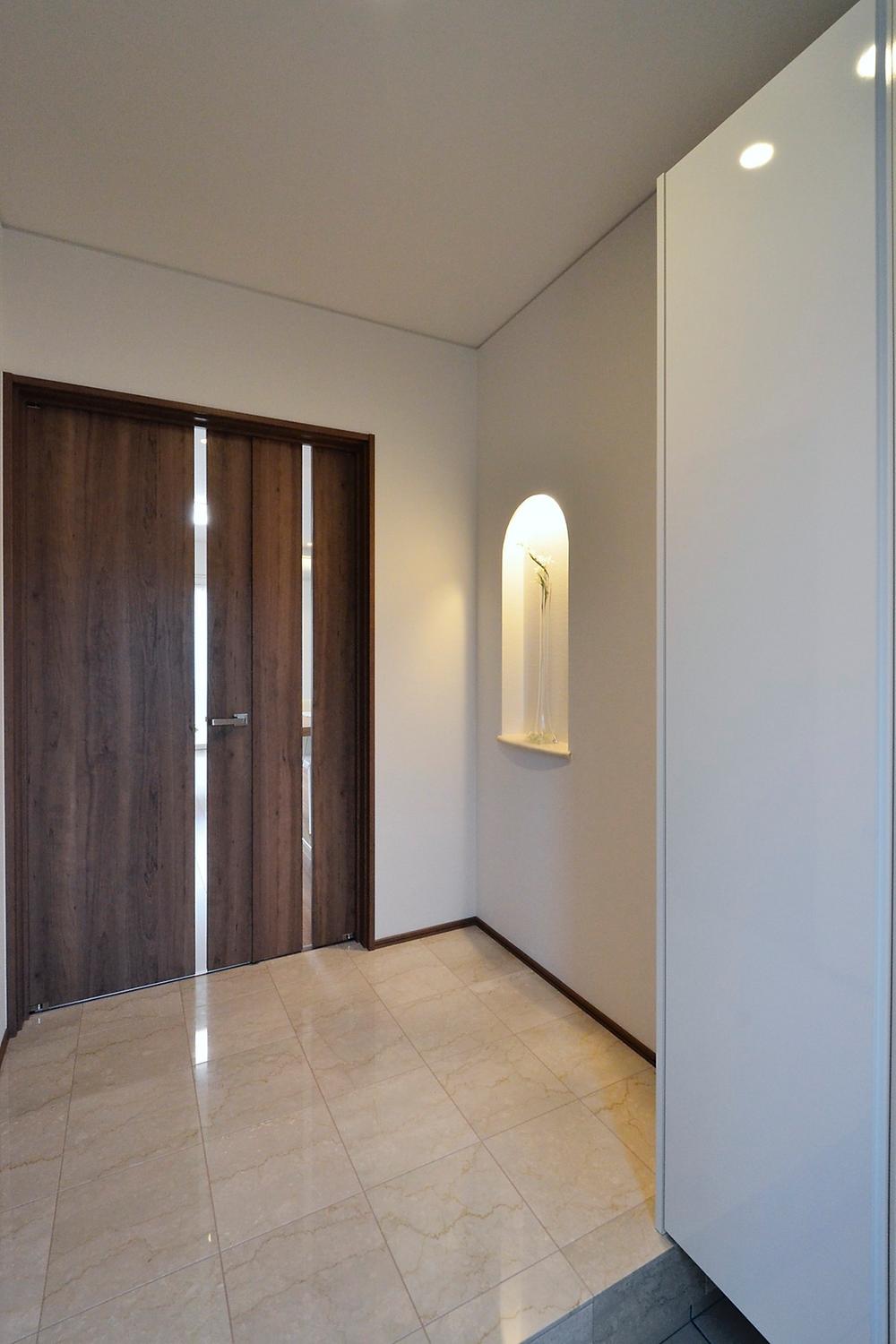 Entrance. Paste the marble on the floor of the entrance hall, It arranged a niche on the wall, Produce a high-quality space to welcome guests. Also cleaner can be stored in a large family by the large shoes BOX. (Local model house)