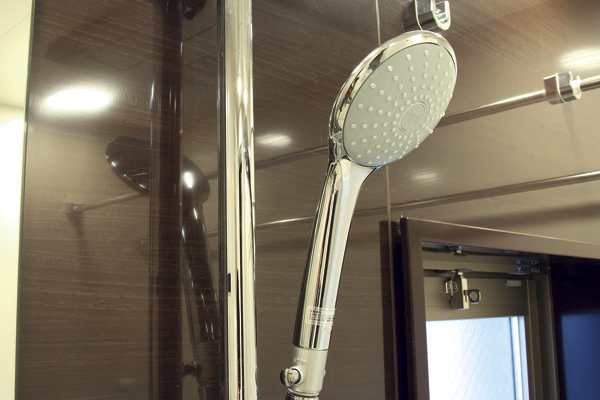 Bathing-wash room.  [Clause with hand button hot water shower head] Adopted the section hot water shower head that can put out stop of hot water at hand. You can stop water diligently, It will be water-saving (same specifications)