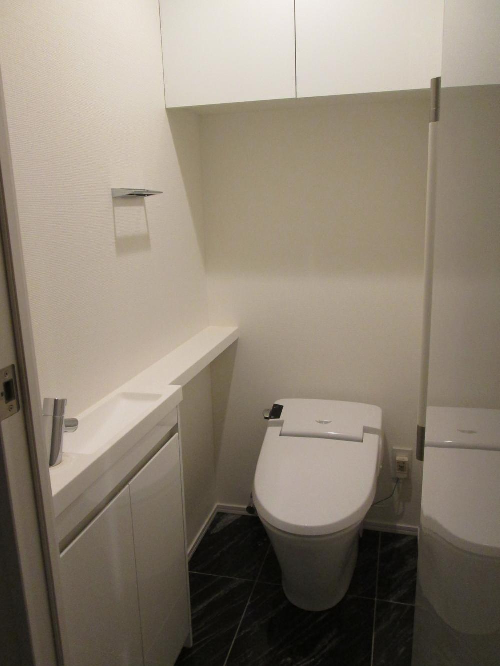 Toilet. Room clean in tankless. The hanging cupboard is possible stock storage.