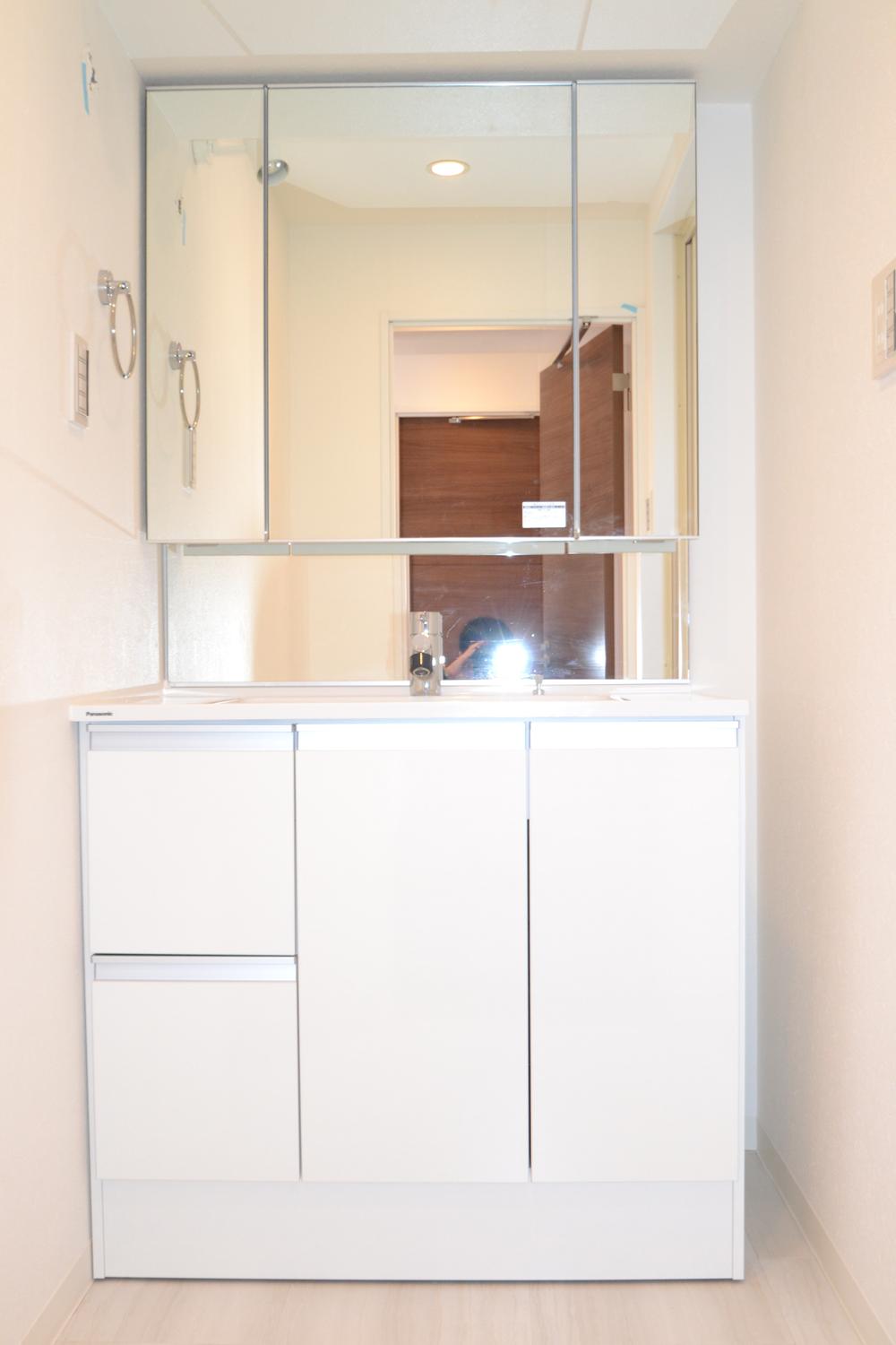 Wash basin, toilet. Vanity with shower. Three-sided mirror.