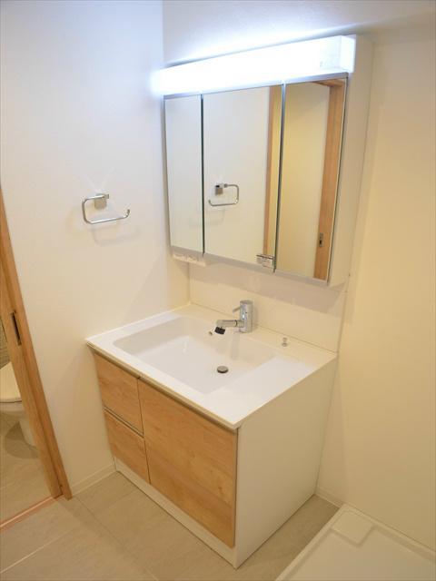 Wash basin, toilet. Three-sided mirror with storage vanity