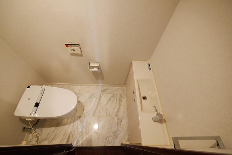 Toilet. Floor and paste natural stone tile, It is with a hand-wash counter to tankless toilet. Width also has secured a spacious space.
