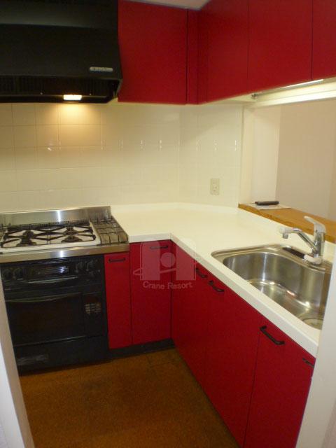 Kitchen. Of fiery red panel color is impressive, L-shaped counter kitchen of firmly comfortable size. Gas Konbekku is built-in.